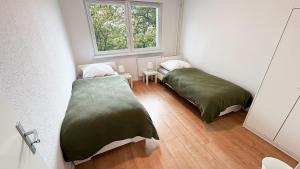 two beds in a small room with a window at Monteurwohnungen mit TV, Internet, Parkplatz, Waschmaschine, Küche, Balkon, Restaurants und Supermarkt in Halle an der Saale