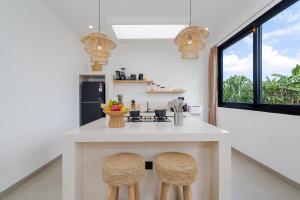 a kitchen with a white island with two stools at Villa Romance in Tumbak Bayuh