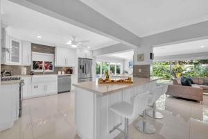 a kitchen with white cabinets and a island with bar stools at Modern Coastal Style Beach Proximity Heated Pool Tranquility Ocean Mist Key RESlDENCES in Fort Lauderdale