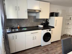 a kitchen with white cabinets and a washing machine at Deluxe Family Appartements Haem in Freiburg im Breisgau