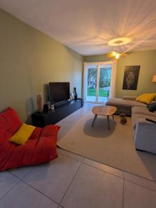 a living room with a red couch and a tv at Villa moderne, piscine & plage in Lattes