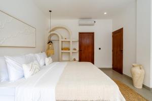 a bedroom with a large white bed with white pillows at Villa Romance in Tumbak Bayuh