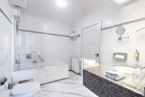 a white bathroom with a tub and a toilet and a sink at Grand Hotel International - Czech Leading Hotels in Prague