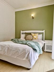 a bedroom with a white bed with a green wall at 70 on Brander in Cape Town