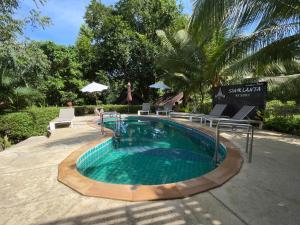 a swimming pool with chairs and a table at Siam Lanta Resort - SHA Extra Plus in Ko Lanta