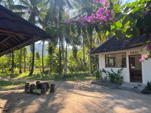 a house with a lot of trees and purple flowers at Kapal dream in Selong Belanak