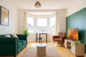 een woonkamer met een groene bank en een stoel bij Walk to Hydro and SEC Modern 3BR Free Parking in Glasgow