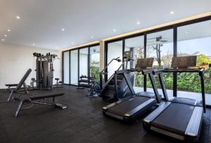 una palestra con tapis roulant ed ellittiche in una stanza con finestre di Sumitra Luxury Villas & Resort by Pramana a Sanur