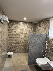 a bathroom with a shower with a toilet and a sink at Phalguni Farm Stay in Nanjangūd