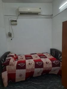 uma cama com um cobertor vermelho e branco e uma televisão em Sai Home Stay em Pondicherry