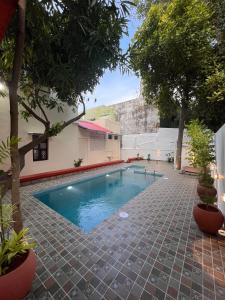 a swimming pool in the middle of a courtyard with trees at L'EDELWEISS Heritage House in Puducherry