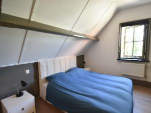 a bedroom with a blue bed and a window at Apartment Sint Maartensbrug near Beach in Sint Maartensbrug