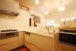 une cuisine avec un évier et une cuisinière dans l'établissement 赤瓦のちいさなお家別邸, à Ishigaki