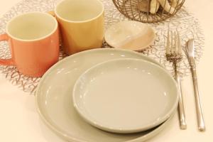 une table avec une assiette et deux tasses et ustensiles dans l'établissement 赤瓦のちいさなお家別邸, à Ishigaki