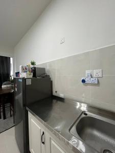 cocina con fregadero y nevera negra en PINAY Home- The Shore Kota Kinabalu, en Kota Kinabalu