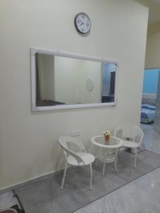 a table and two chairs and a clock on a wall at Marissa Homestay 