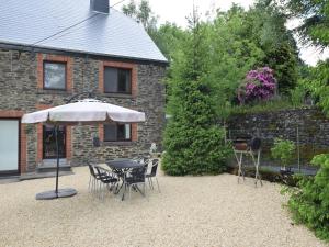 a patio with a table and chairs and an umbrella at Cottage in Ardennes with Heated Pool in Warempage