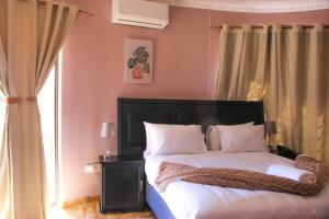 a bedroom with a bed with white sheets and a window at Masiyabundu chalets in Gaborone