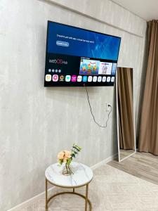 einen an einer Wand hängenden TV mit einem Tisch und einem TV in der Unterkunft 1,5-комнатная квартира в центре города in Öskemen