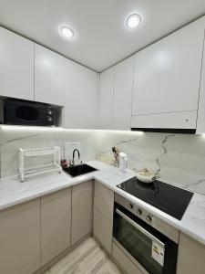 eine weiße Küche mit Spüle und Herd in der Unterkunft 1,5-комнатная квартира в центре города in Öskemen