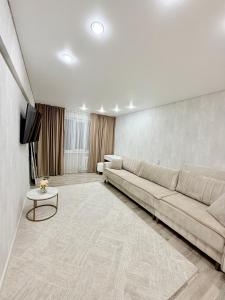 ein Wohnzimmer mit Sofa und Fernseher in der Unterkunft 1,5-комнатная квартира в центре города in Öskemen