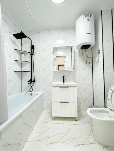 Un baño blanco con bañera, lavabo e inodoro. en ЖК Millennium, en Bishkek