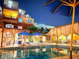 a swimming pool with umbrellas and chairs and a building at Nile Compound in Luxor