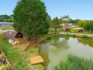 a small pond with a house in the middle at Lakeside Haven -Fishing Lakes, Heated Outdoor Swimming Pool 500yrds on Sister Park , Pool Open May to September in Cheriton Bishop