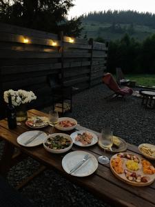 a wooden table with plates of food and glasses of wine at Stryh xata - Будиночок в Карпатах з чаном-джакузі in Volosyanka