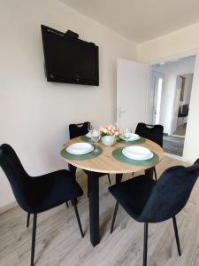 a dining room table with chairs and a television on a wall at Apartman Sky 1 in Gornja Toplica