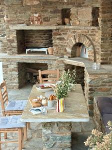 a table and chairs with a stone pizza oven at Villa AVRA, a serene Cycladic villa with private pool overlooking the Aegean Sea in Batsi