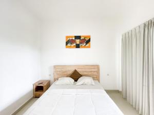 a bedroom with a large bed with white sheets at Urbanview Hotel Lilis Ikvala Radha in Canggu +20 photos