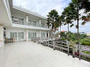 a large white building with a balcony and palm trees at Urbanview Hotel Lilis Ikvala Radha in Canggu