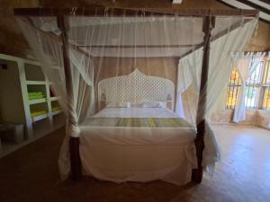 a bedroom with a canopy bed with white curtains at Katiti N'tamu Lamu in Lamu