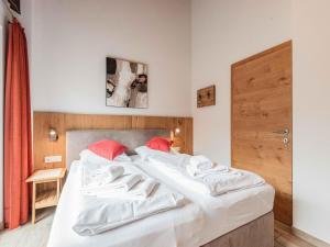 a bedroom with a bed with white sheets and red pillows at Chalet in Niedernsill near Ski Slopes in Niedernsill