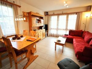 a living room with a red couch and a table at Family Stay in Aletsch Alps in Bellwald +26 photos
