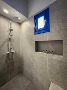 a bathroom with a shower with a blue window at Evgenia Rooms and Apartments in Chora Folegandros