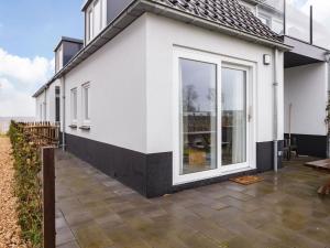 a white house with large windows and a patio at Apartment located directly on the Sneekermeer in Offingawier