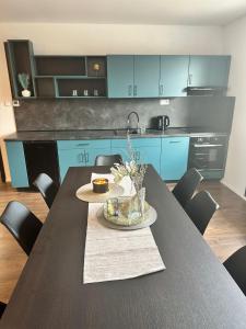 a kitchen with blue cabinets and a table and chairs at Ubytování Včelka - Novohradské hory - Svébohy in Horní Stropnice