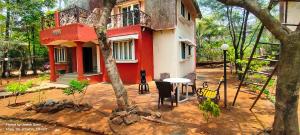 a red and white house with a table in front of it at Marigold Bungalow in Kelavli