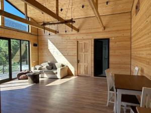 a living room with wooden walls and a table and chairs at Tetnuldi River Chalet in Mestia