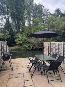 eine Terrasse mit Tisch und Stühlen und einem Sonnenschirm in der Unterkunft Rickmansworth Lodge in Rickmansworth + 5 Fotos