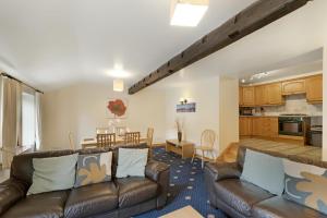a living room with two leather couches and a kitchen at Bank View Barn at Pound Farm in Crook