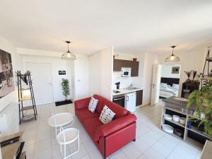 a living room with a red couch and a kitchen at Charmant T2 avec grande terrasse in Saint-Nazaire