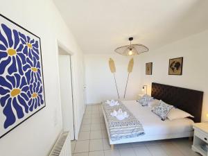 a bedroom with a bed with a blue and yellow painting on the wall at Charmant T2 avec grande terrasse in Saint-Nazaire