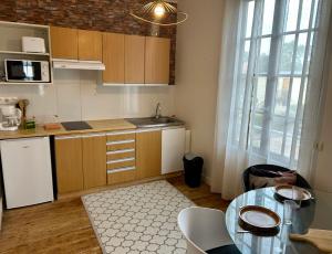 a kitchen with wooden cabinets and a table and a window at Mer & Côte Fleurie Plage à pied in Merville-Franceville-Plage