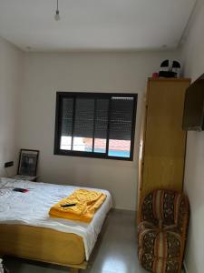 Un dormitorio con una cama y una ventana y una silla. en Appartement 50 m Ocean, en Kenitra