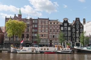 un grupo de barcos atracados en el agua frente a los edificios en art deco houseboat on super location, en Ámsterdam