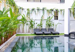 ein Pool mit zwei schwarzen Bänken neben einer weißen Wand mit Pflanzen in der Unterkunft iThaphae Hotel in Chiang Mai