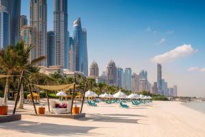 a beach with chairs and umbrellas in front of a city at One&Only Royal Mirage Resort Dubai in Dubai +108 photos